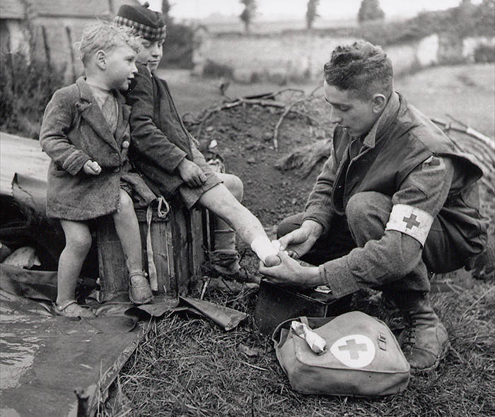 A medic tends to this little boy's injuries, while his younger brother watches quietly.