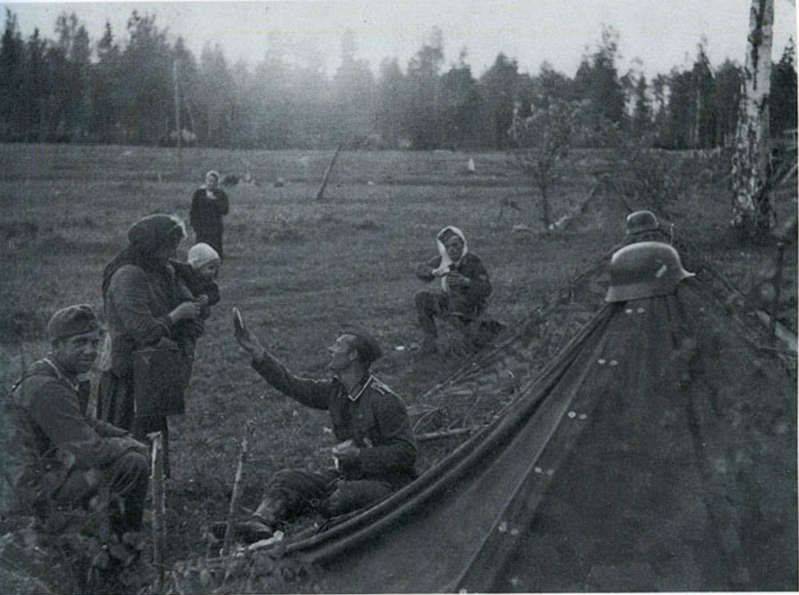 A German soldier shares his rations with a Russian mother and her child. [World War II, c. 1941]