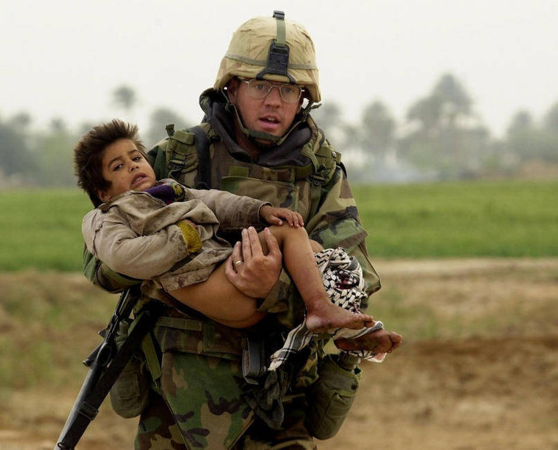 Joseph Dwyer rushes an injured boy away from fire and to safety. [Iraq War, c. 2003 - 2011]