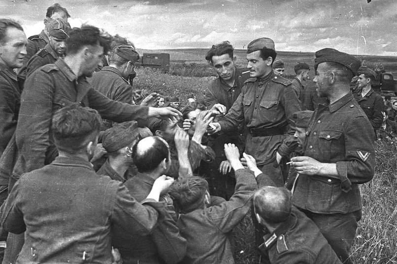 A Soviet soldier shares his cigarettes with German prisoners. [World War II, July, 1943]