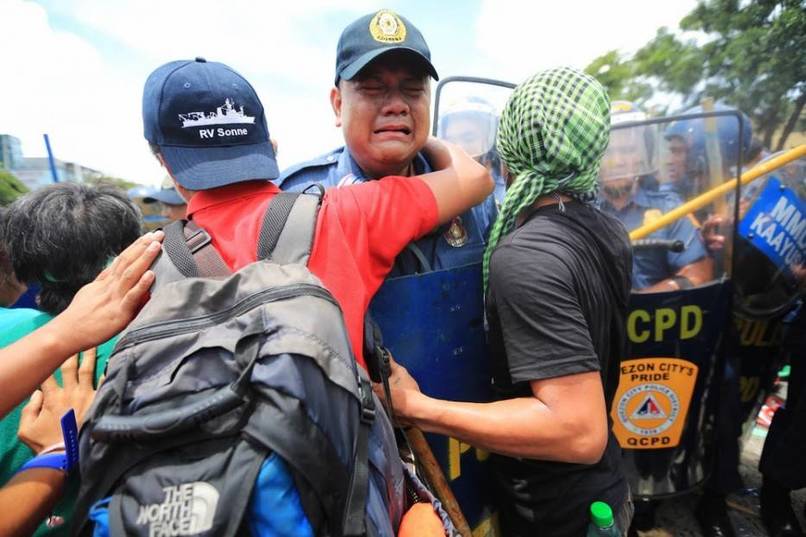 Officer Joselito Sevilla is comforted after being berated by a protester. [Manila, Philippines, 2013]