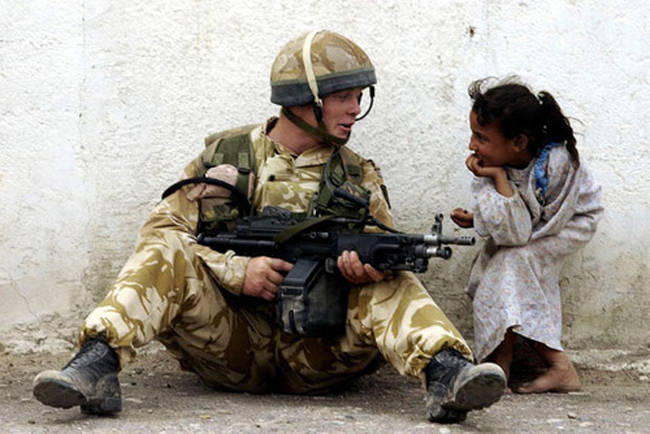 A soldier stops to chat with a little girl. [2011]