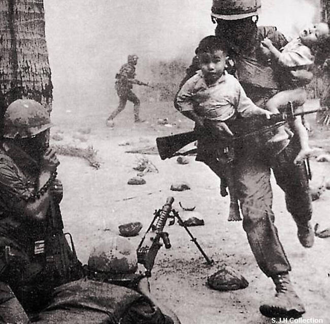 A soldier runs from the battlefield as he rescues two Vietnamese children from harm's way. [Vietnam War, c. 1955 - 1975]