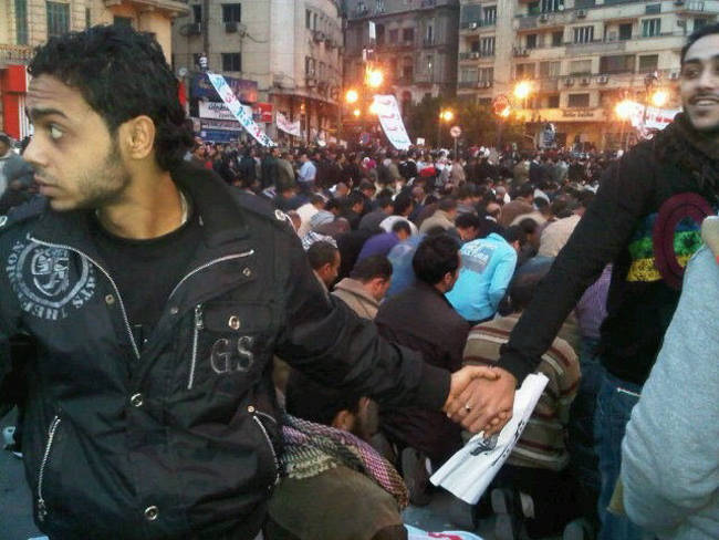 Christians create a barrier, protecting Muslims as they pray during the Egyptian revolution. [Cairo, Egypt, 2011]