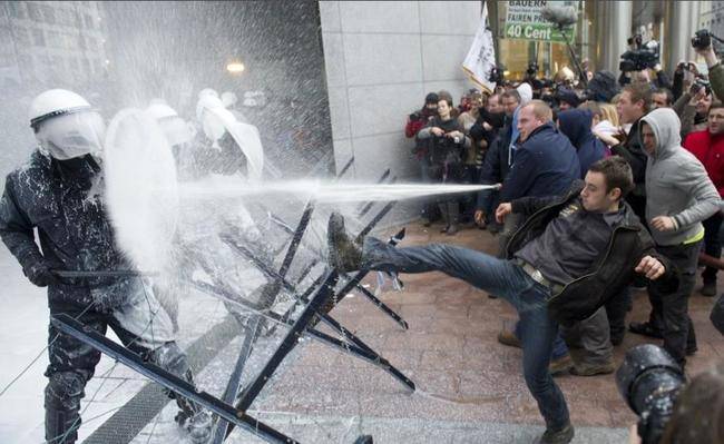 In Brussels, EU dairy farmers protest by using milk canons on officers.