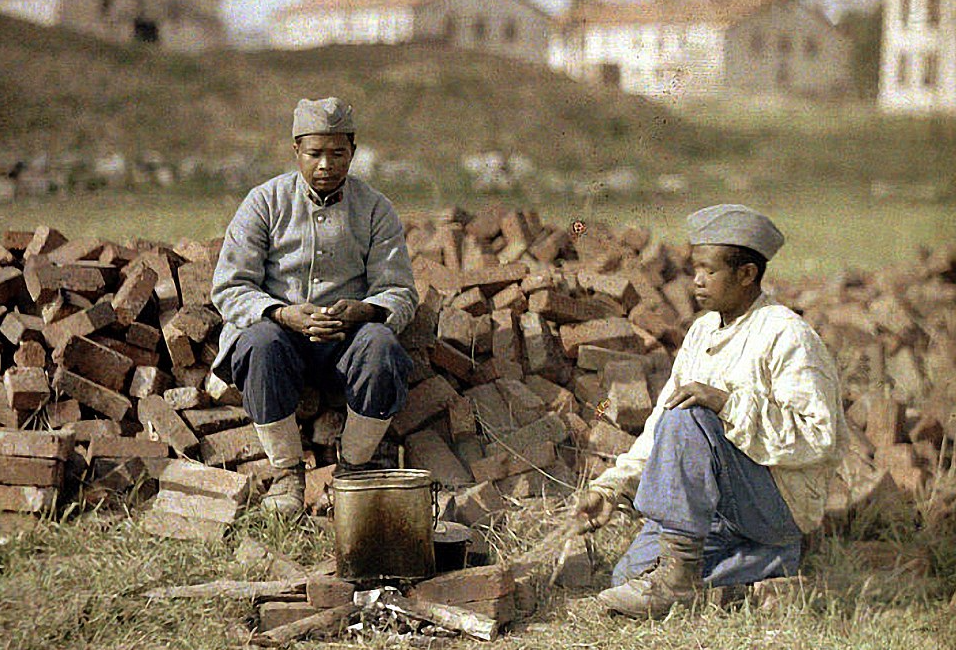 Two French soldiers from Africa cooking a meal on a makeshift fireplace made from bricks in Soissons, Aisne, France: