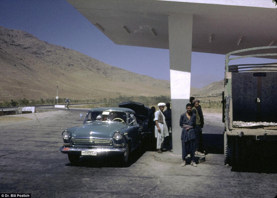 Men stand next to their gleaming car at a petrol station