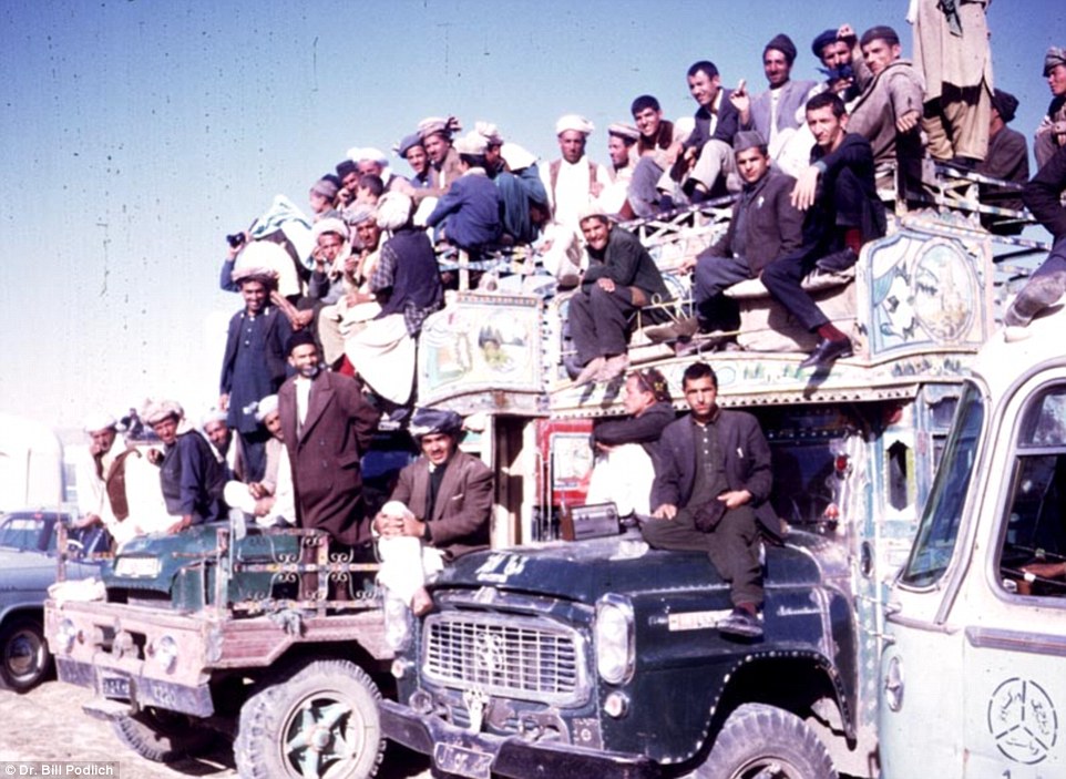 Happy citizens gather on the roof of trucks for a group photograph.