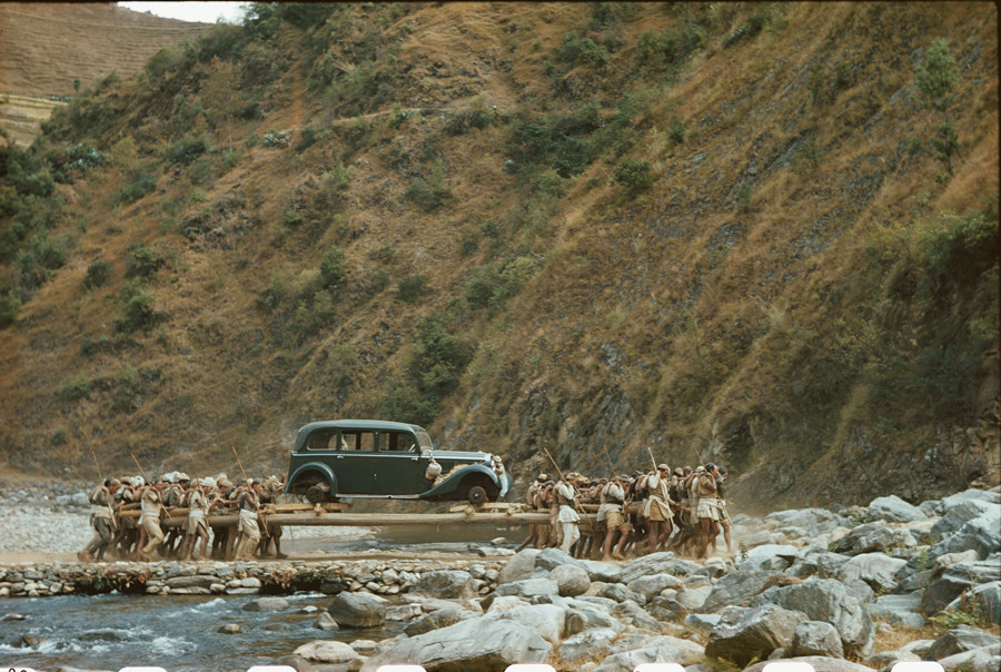Native porters transport Rolls-Royce on poles across remote river in Nepal, January, 1950