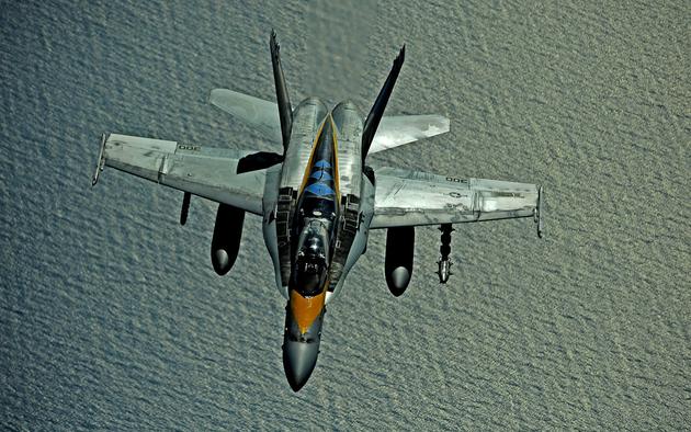 A U.S. Navy FA-18 flies over the ocean on a refueling mission.