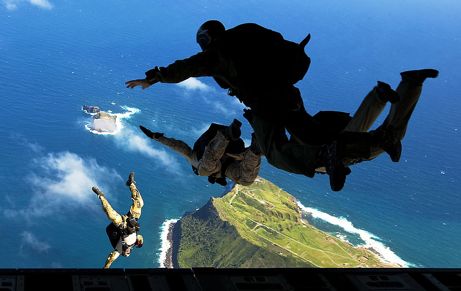 Air Force pararescuemen from 103rd Rescue Squadron, 106th Rescue Wing, New York Air National Guard, and West Coast-based Navy SEALs leap from the ramp of an Air Force C-17 transport aircraft during free-fall parachute training over Marine Corps Base Hawaii.
