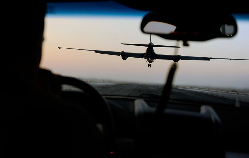 A chase vehicle drives behind a U-2 Dragon Lady to communicate altitude and alignment corrections while it lands at an undisclosed location in Southwest Asia.