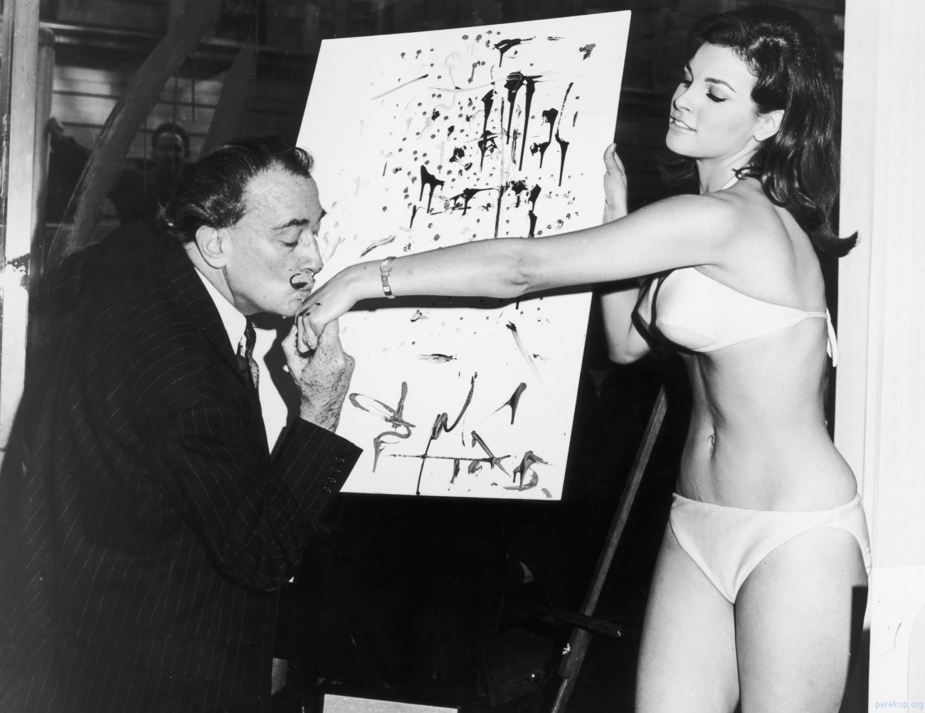 Salvador Dal kisses 25-year-old Raquel Welchs hand in front of his abstract portrait of her, 1965