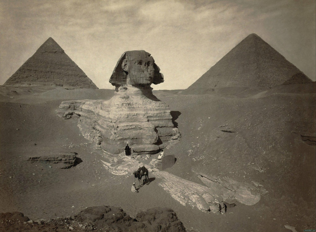 A late nineteenth century photo of the partially excavated Great Sphinx of Giza, with the Pyramid of Khafre -left- and the Great Pyramid of Giza -right- behind it