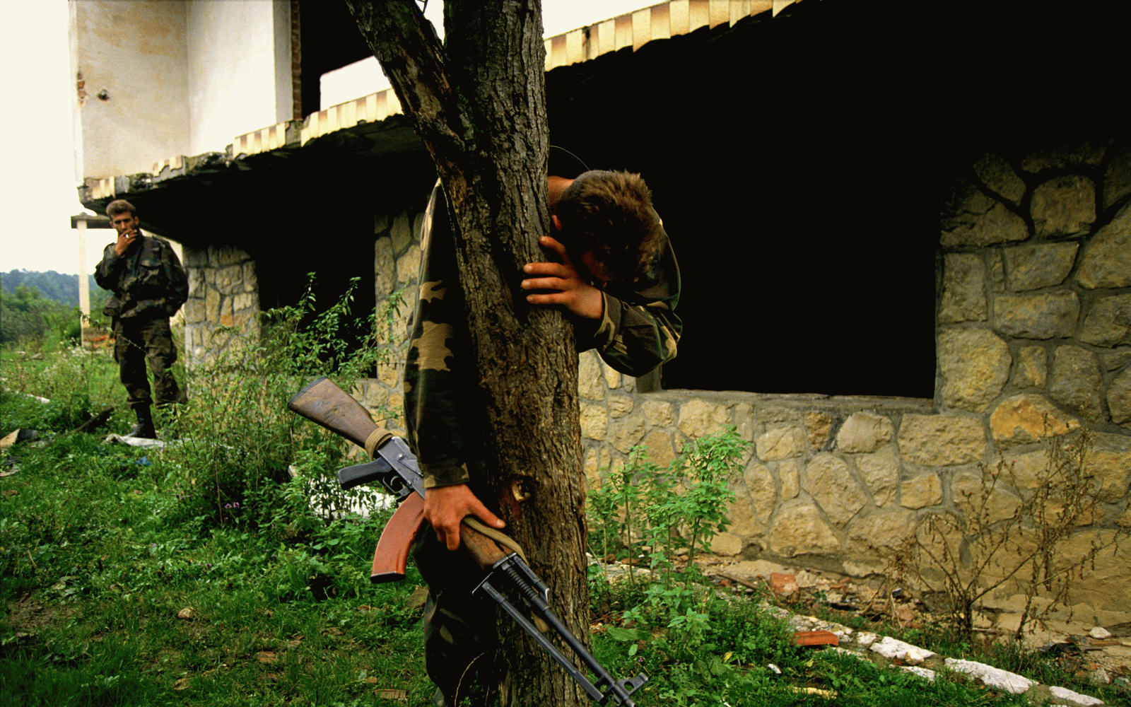 A Bosnian soldier stands on what is believed to be a mass grave outside his destroyed home. He was the sole survivor of a massacre that left 69 people dead, including his family.