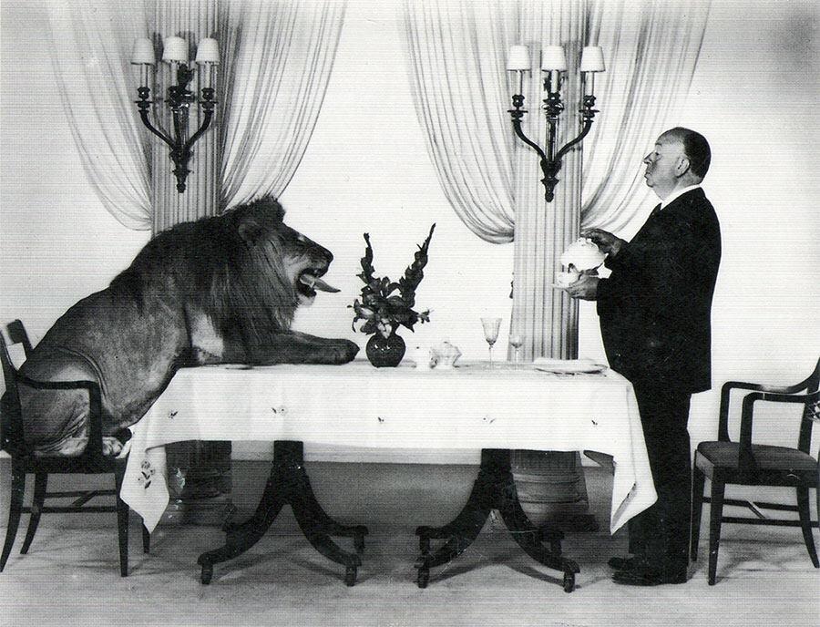 Alfred Hitchcock serving tea to Leo the Lion, the mascot for the Hollywood film studio MGM, 1957