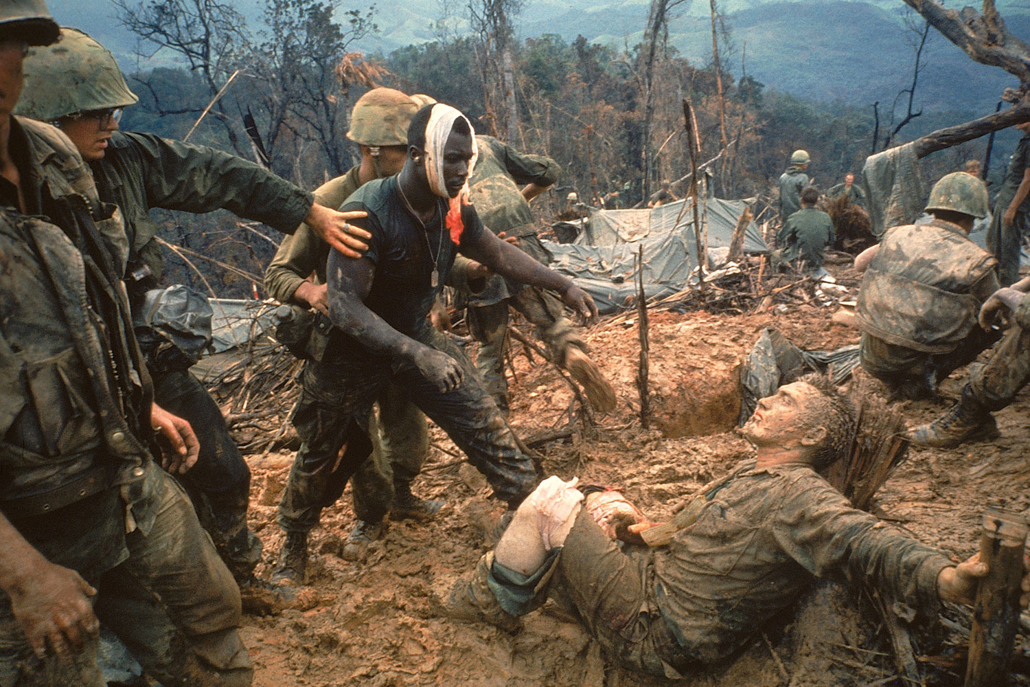 Wounded Marine Gunnery Sgt. Jeremiah Purdie moves to comfort a stricken comrade after a fierce firefight for Hill 484 during the Vietnam War, 1966