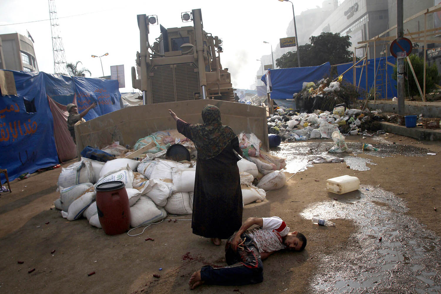 Woman defends a wounded protester from a military bulldozer. Egypt, 2013