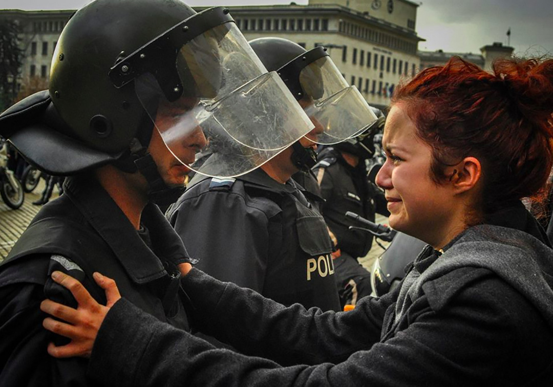 Riot police and protesters share a cry together. Sofia, Bulgaria, 2013