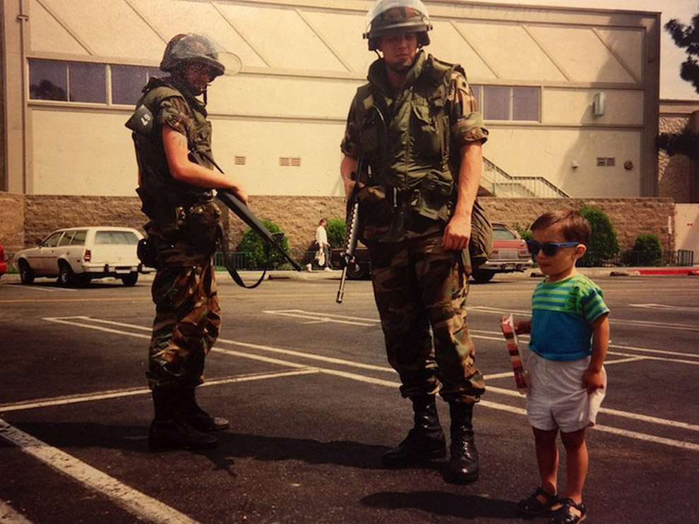 A child poses beside National Guard members during the LA Riots. Los Angeles, USA, 1992