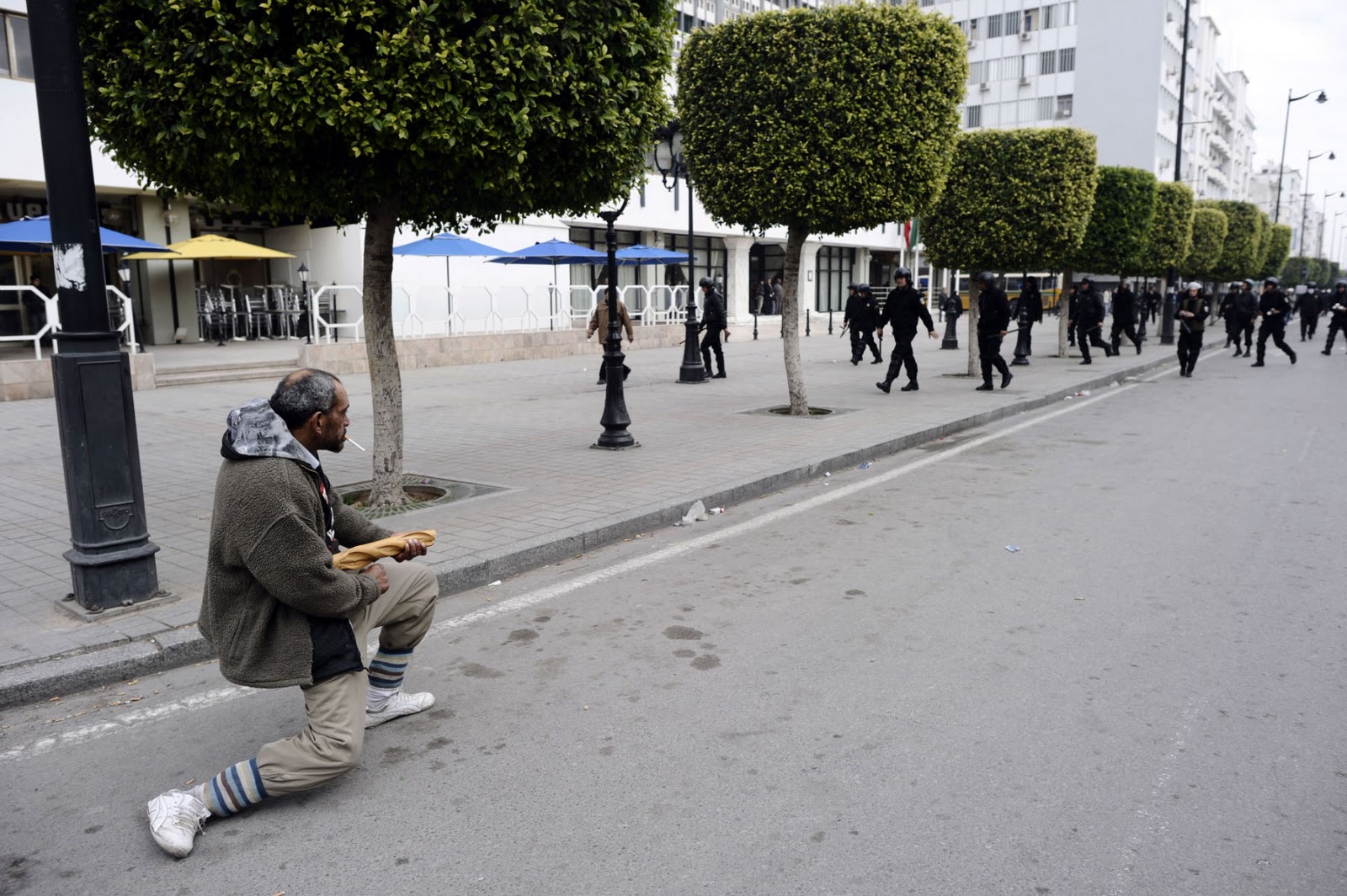 Tunisian man holds back riot police with a baguette during the revolution. Tunisia, 2010-11