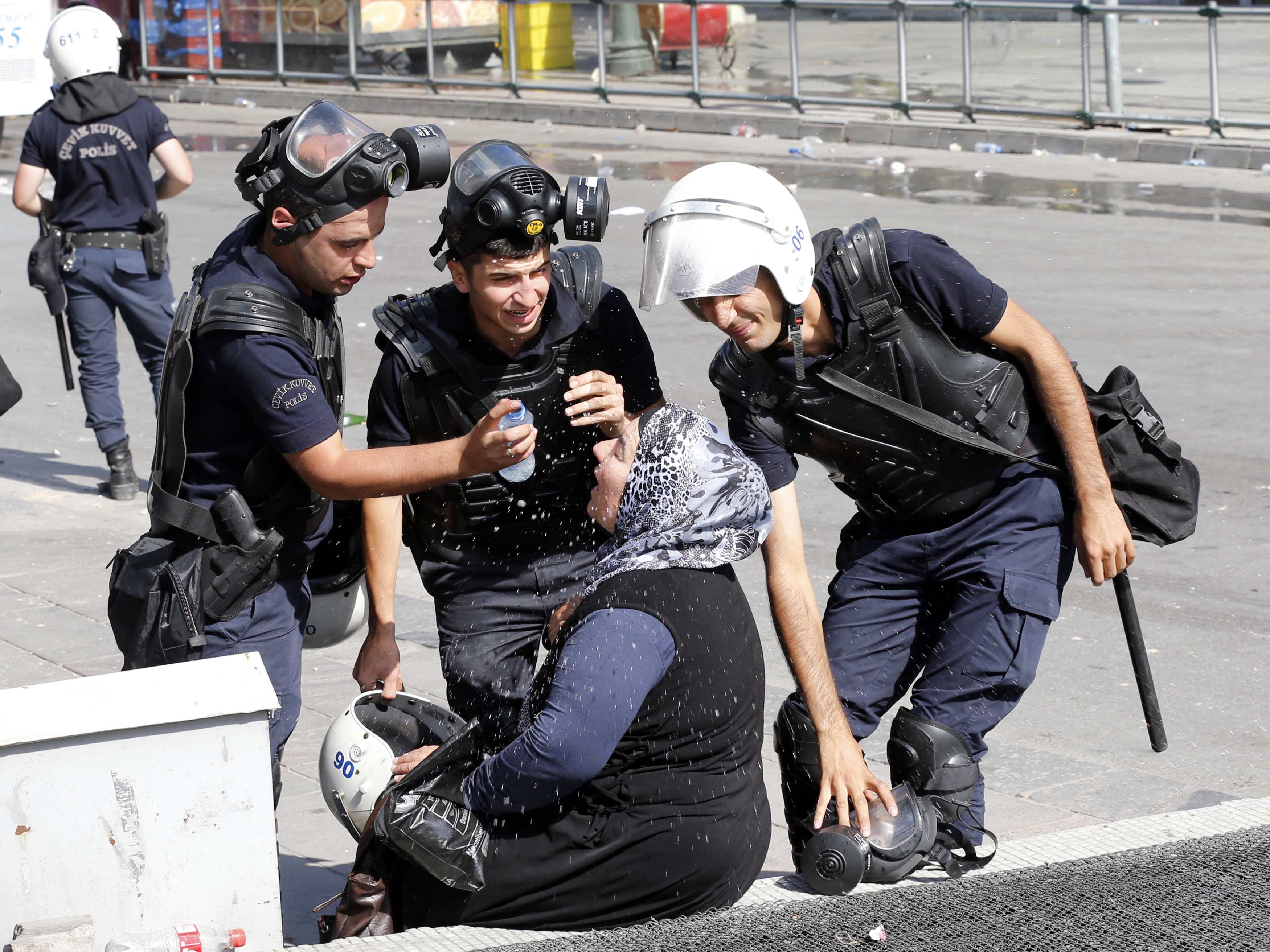 Riot police help a woman affected by tear gas. Ankara, Turkey, 2013