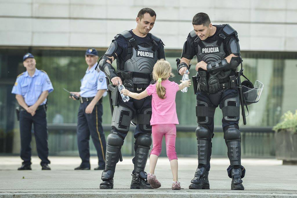 Girl hands water to two officers. Bosnia, 2013