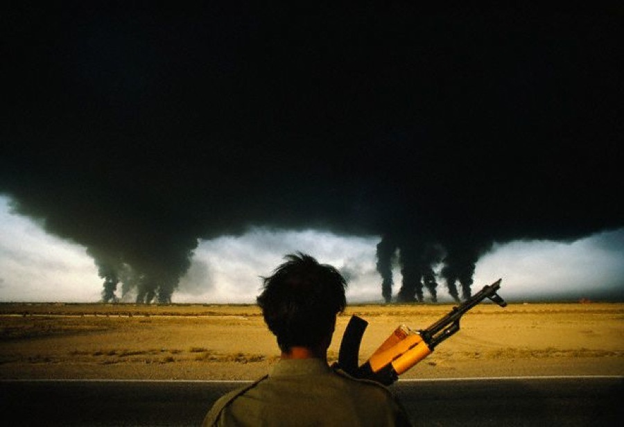 An Iranian soldier looks out over the desert, darkened under clouds of burning oil set alight by Iraqi forces in 1990.