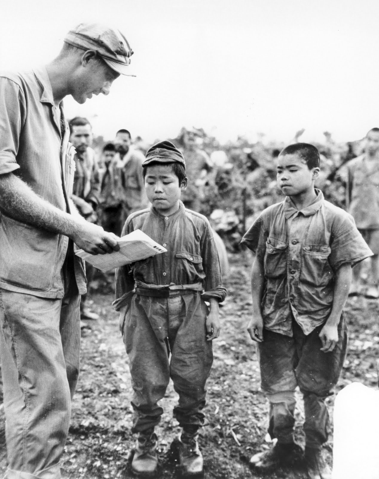 An American Marine tries to communicate with two Japanese child soldiers captured on Okinawa, June 1945