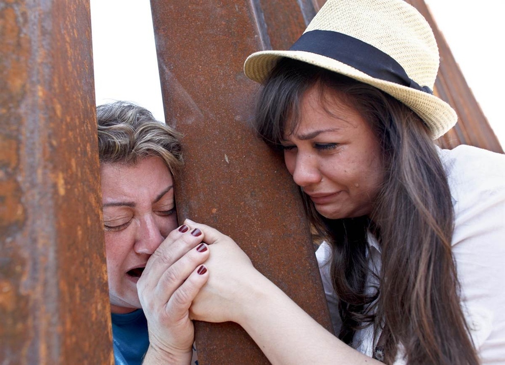 Renata Teodoro, 25, right, holds hands with her mother, Gorete Borges Teodoro, who was deported six years ago from the U.S., through the bars of a border fence in Nogales, Ariz.