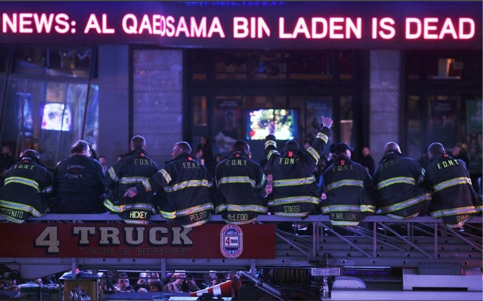 Firefighters of Ladder Company 4, which lost seven men on 911, perched together on their aerial ladder, watching a news bulletin in Times Square declaring that Osama bin Laden was dead