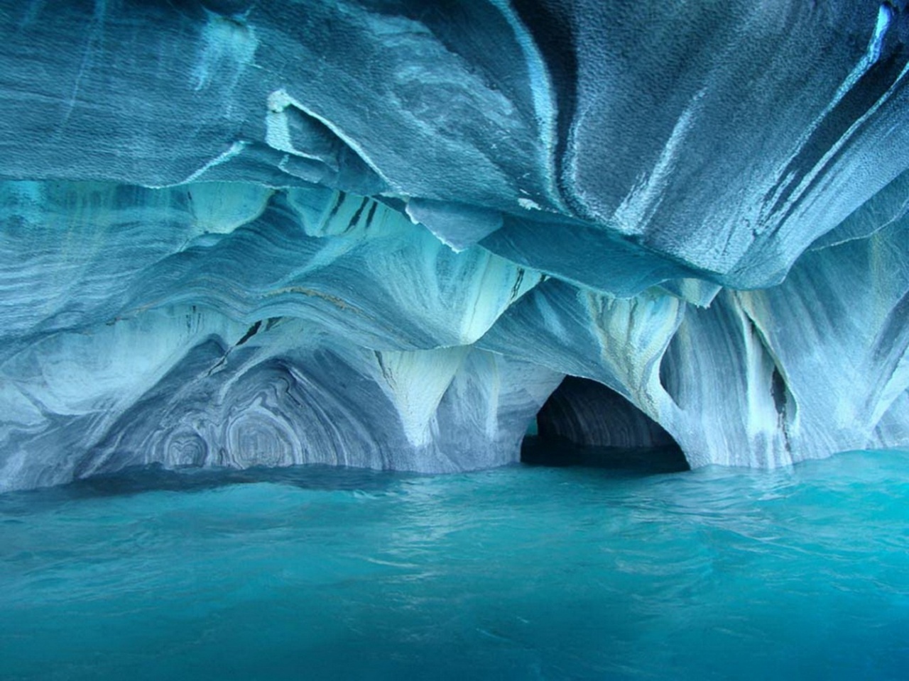 Marble Caves Chile- Crystal-clear water tinted a dazzling blue by glacial silt accentuates the intricate designs in what many call he most amazing cave network in the world. The water is also responsible for forming the unique shape of the caverns and walls, making an Earthly cave appear very otherworldly.