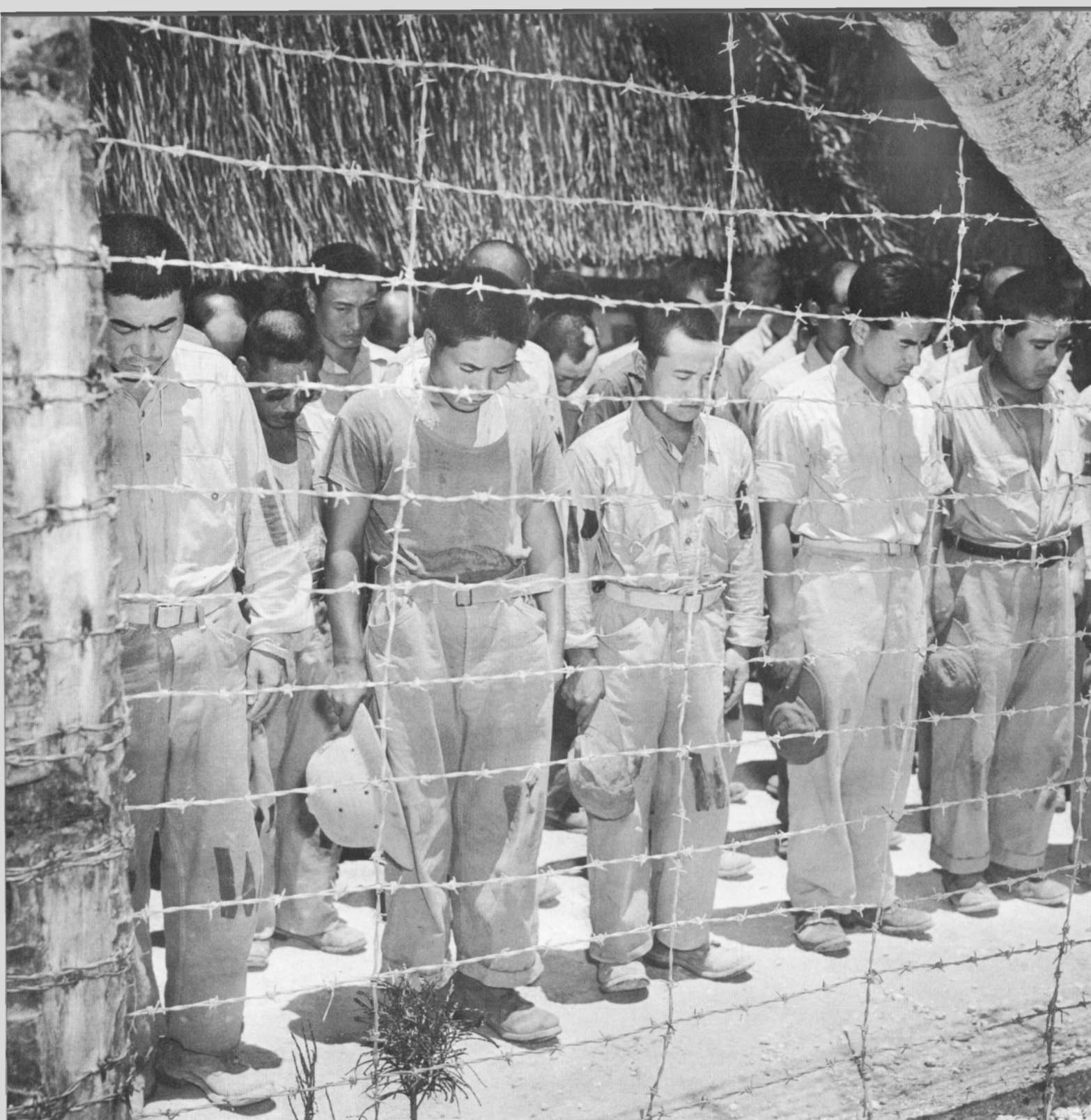 Japanese prisoners of war at a POW camp with bowed heads as they heard Emperor Hirohito broadcast the unconditional surrender of Japan.