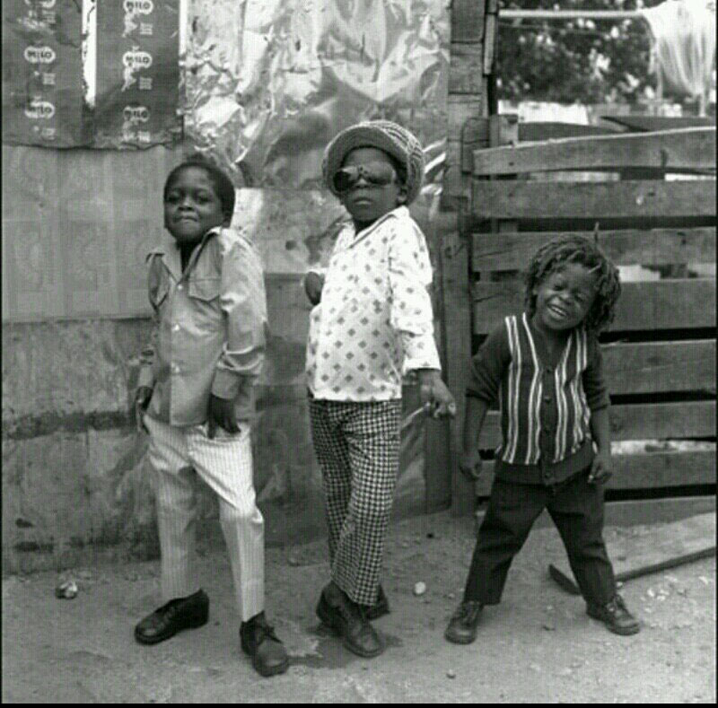 Three boys pose for a camera on the streets of Jamaica