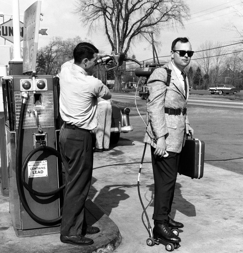A salesman has his motorized roller skates refueled at a gas station, 1961
