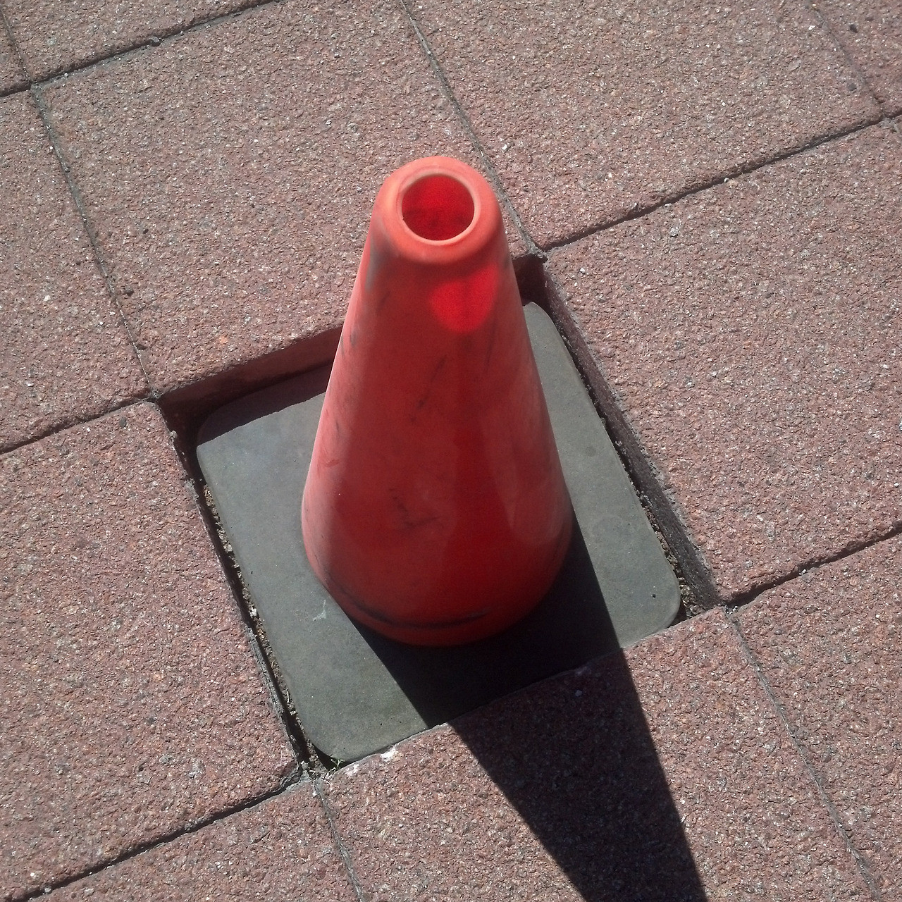 A traffic cone fitting flawlessly into a patio.