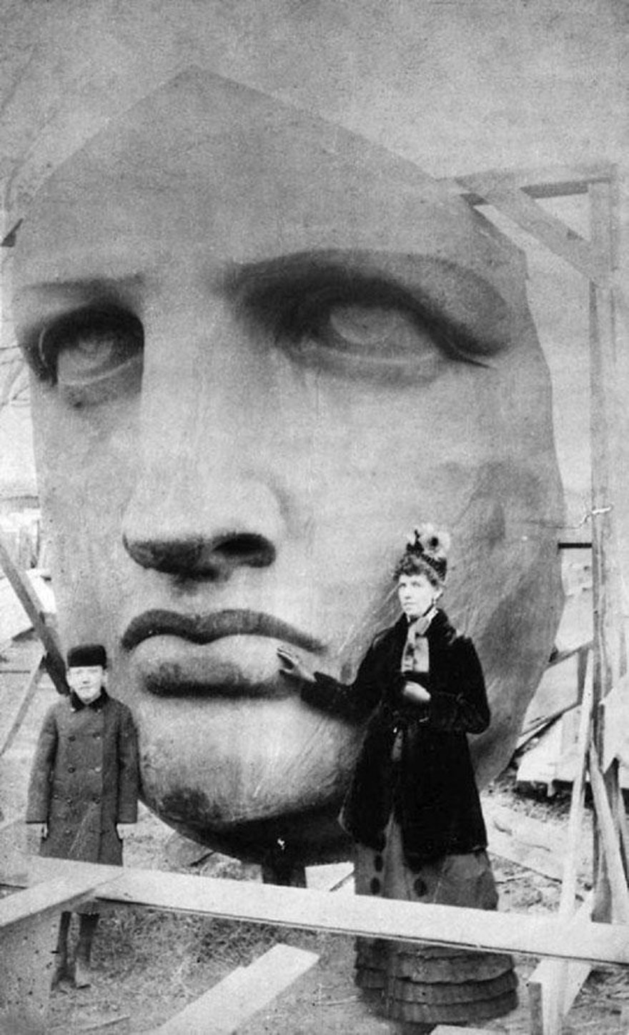 People posing next to the Statue of Liberty as it's unpacked, 1886.