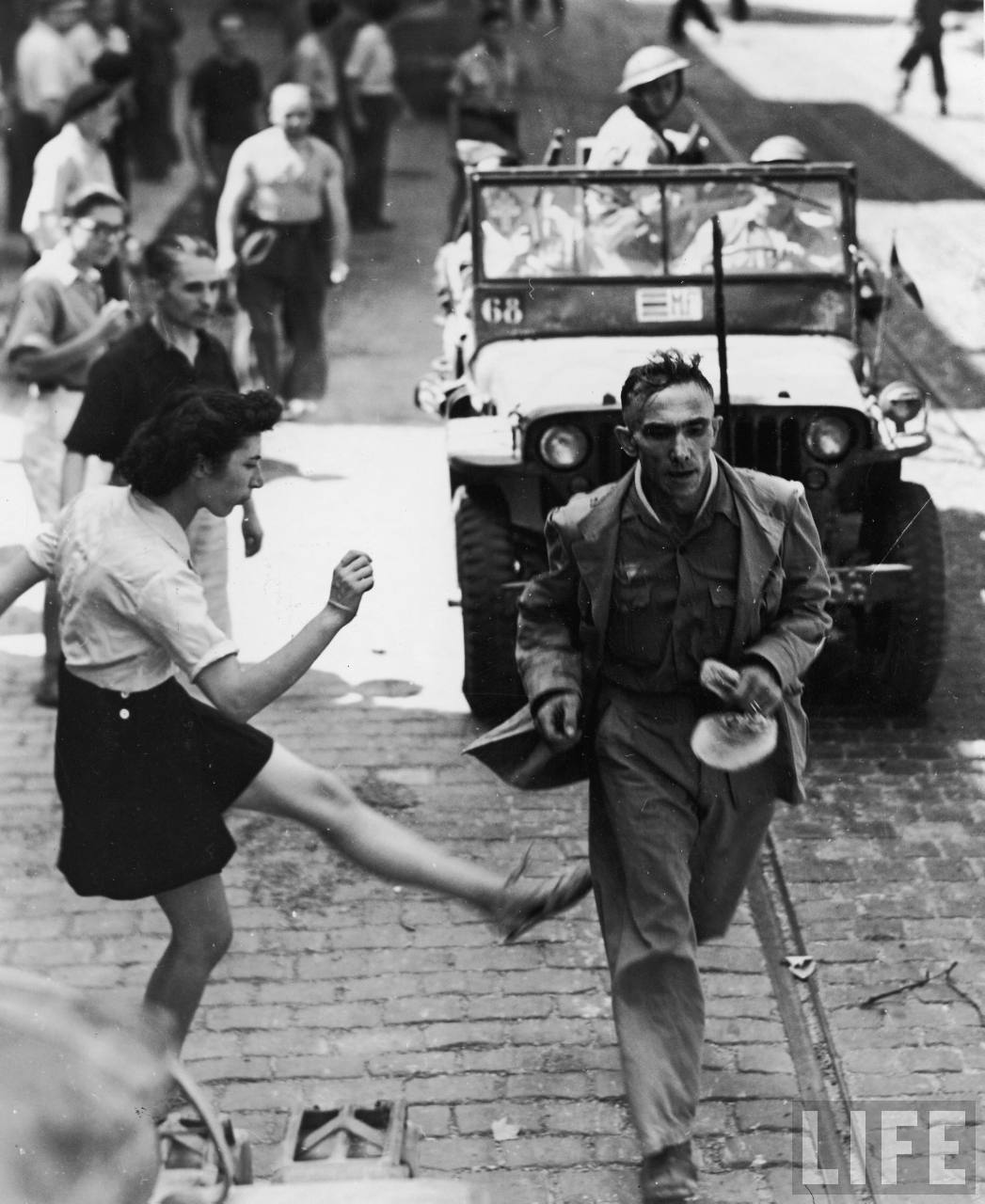 French girl vents anger by kicking at a passing German prisoner on his way to confinement after being captured. September 26, 1944