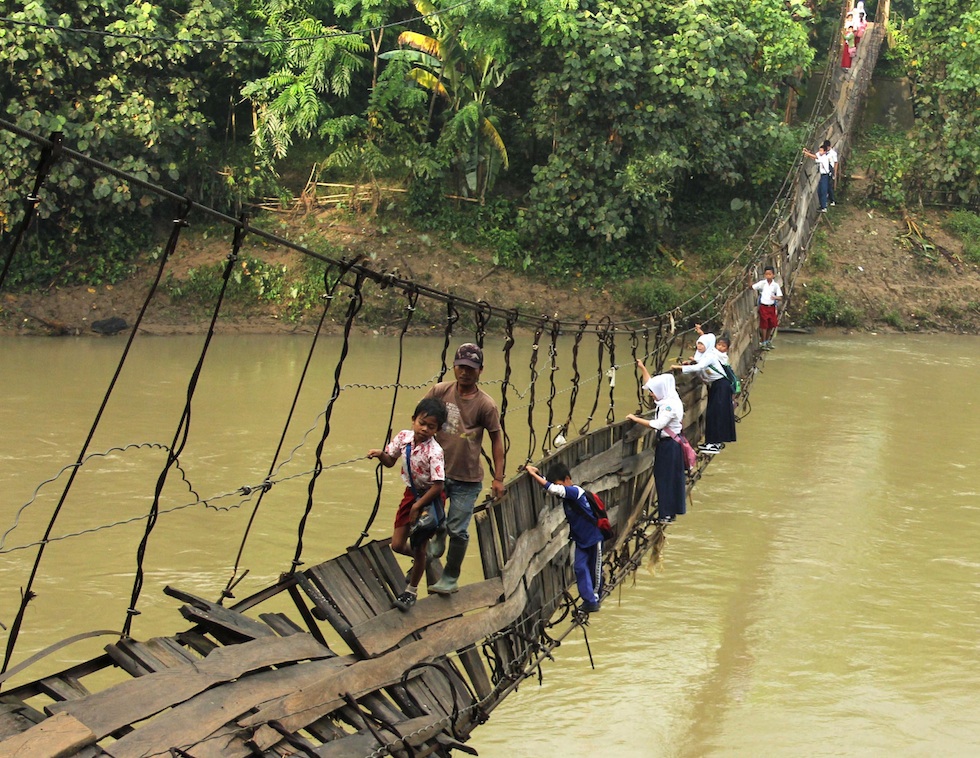 Pupils crossing a damaged suspension bridge in Lebak, Indonesia