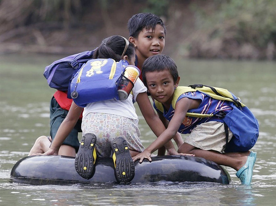 Elementary school students crossing a river on inflated tire tubes in Rizal Province, Philippines
