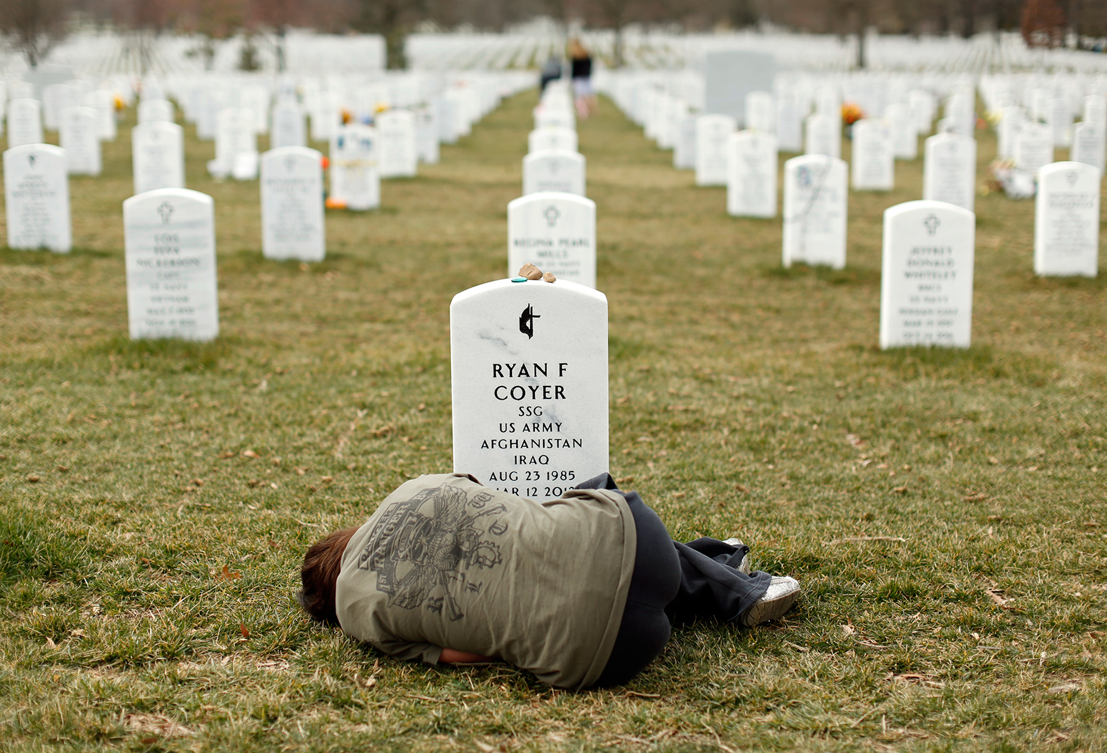 Lesleigh Coyer, 25, of Saginaw, Michigan, lies down in front of the grave of her brother, Ryan Coyer, who served with the U.S. Army in both Iraq and Afghanistan, at Arlington National Cemetery in Virginia March 11, 2013. Coyer died of complications from an injury sustained in Afghanistan.