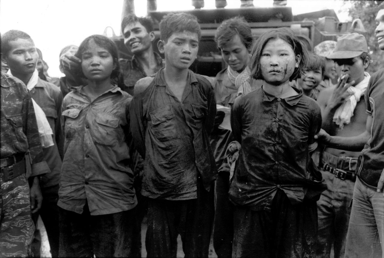 Soldiers parade terrified young prisoners on the streets of Cambodia in 1974. The prisoners were later stripped, violated and murdered.