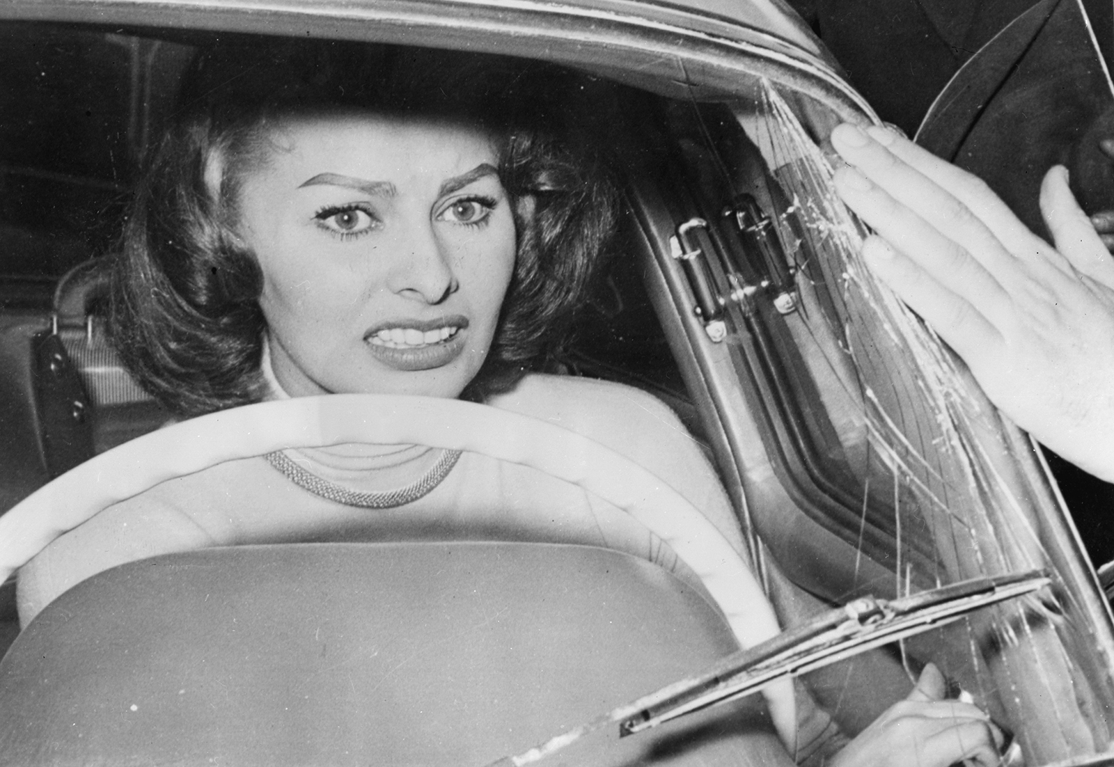Sophia Loren cowers in her car as a crowd of fans press around her, smashing the windscreen in their eagerness to see her, April 9, 1956, Rome.