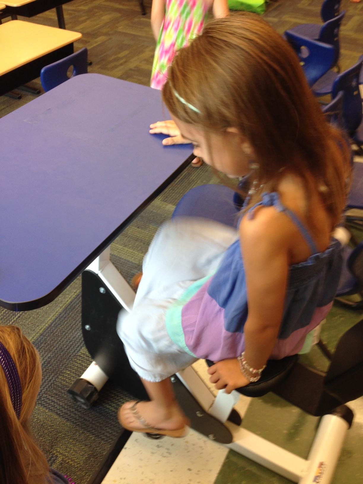 This first grade classroom has desks with pedals so kids can move while learning.