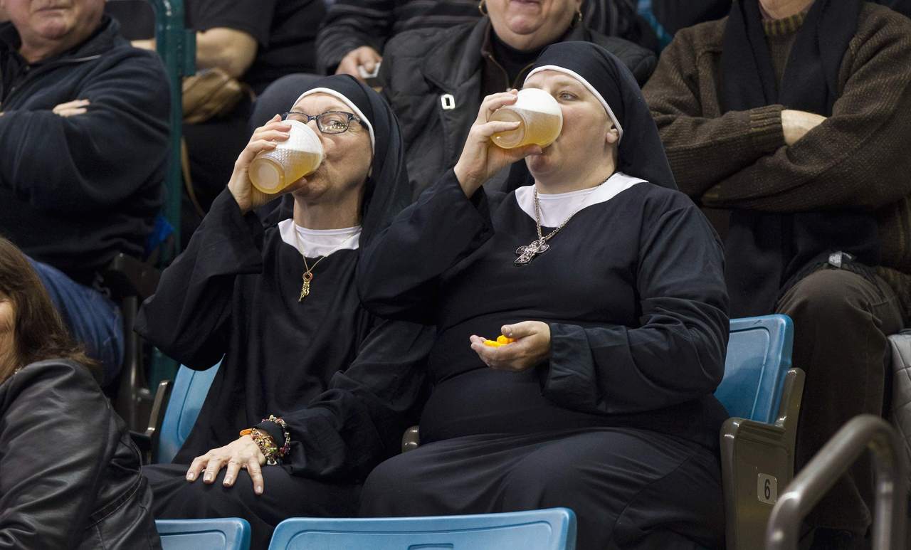 Two women wearing nun outfits drink beer while watching the playoff draw between Quebec and Manitoba at the 2014 Tim Hortons Brier curling championships in Canada on March 8.