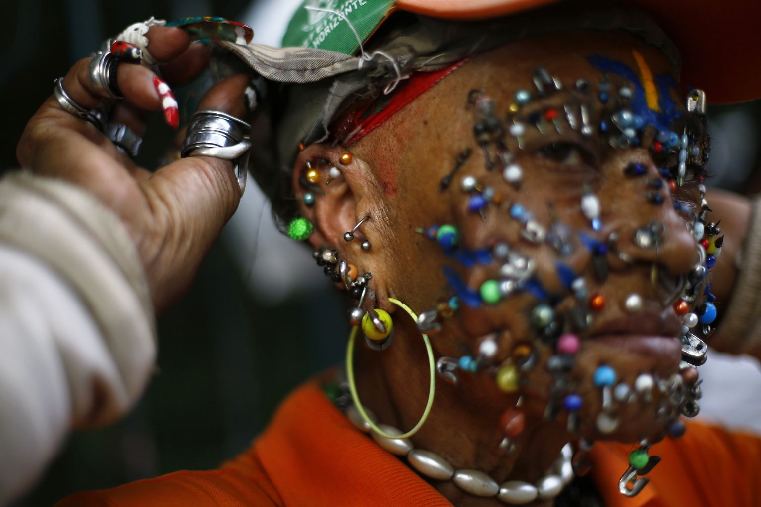 A street cleaner and fan of the Brazilian national World Cup soccer team shows the myriad of piercings on her face on a street in Belo Horizonte, July 3, 2014.