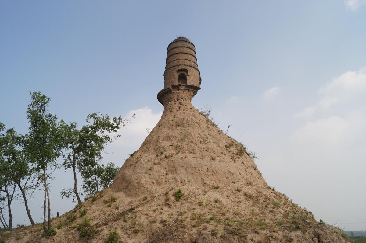 An ancient tower is seen balancing on top of a dirt hill with its base almost entirely eroded along a grassland in Shanxi province, China in July.