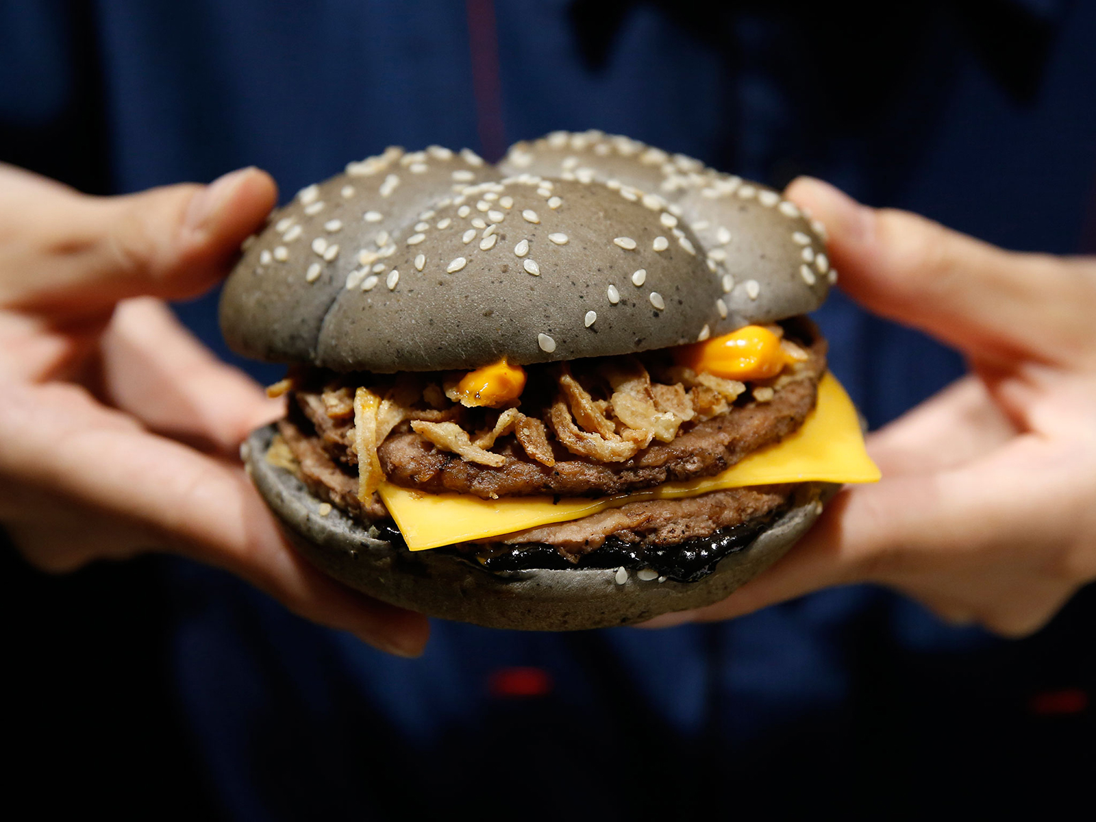 An employee of McDonald's Japan holds an Ikasumi, "squid ink" burger at one of its fast-food outlets in Tokyo in October. McDonald's Japan launched the Halloween-themed black burger, which have buns made from a flour mix of bamboo charcoal powder and black sesame to create the charred look, and beef patties marinated with squid ink sauce. The burger is priced at 370 yen or 3.40 dollars.