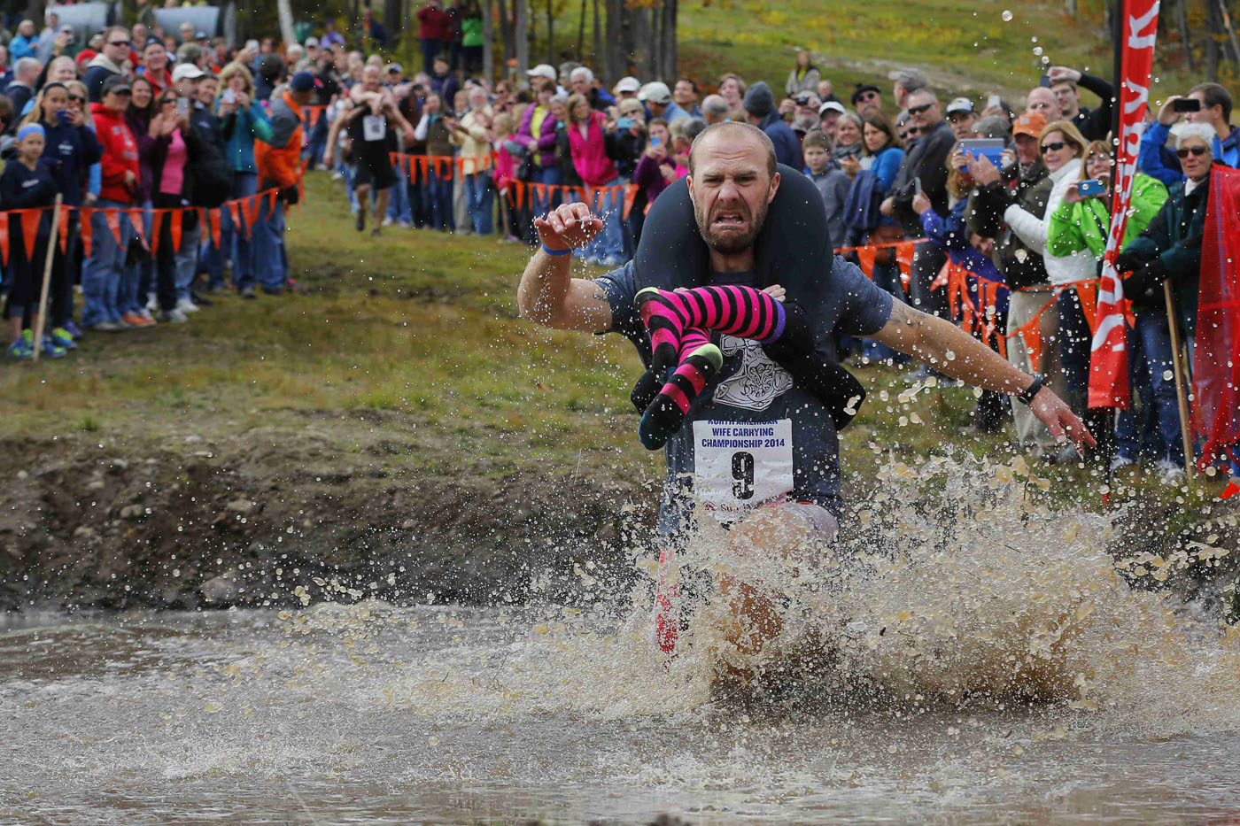 Eventual winners Jesse Wall carries Christina Arsenault through the water pit while competing in the North American Wife Carrying Championship at Sunday River ski resort in Newry, Maine on Oct. 11.