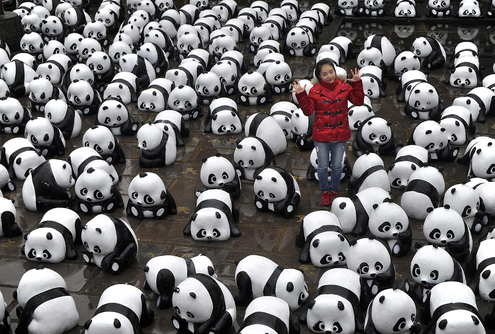 A woman poses for pictures among panda installations during an exhibition in Hefei, China.